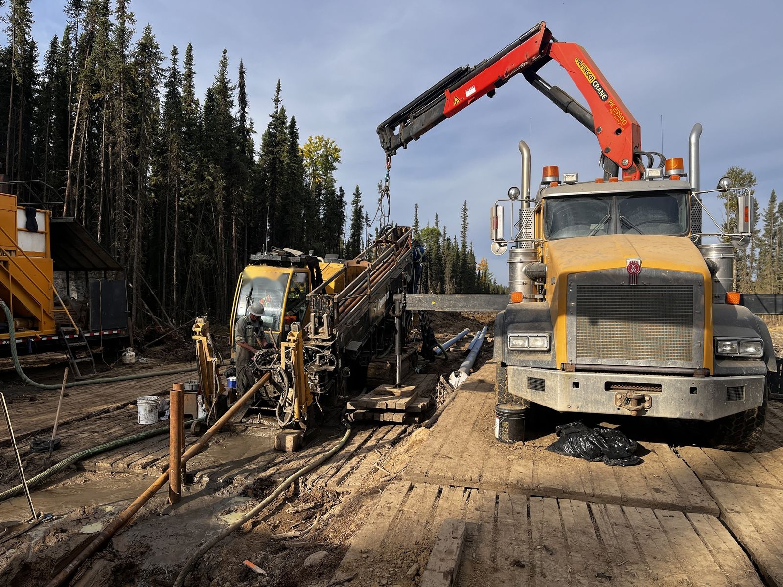Crew at the rig with the picker truck loading drill pipe